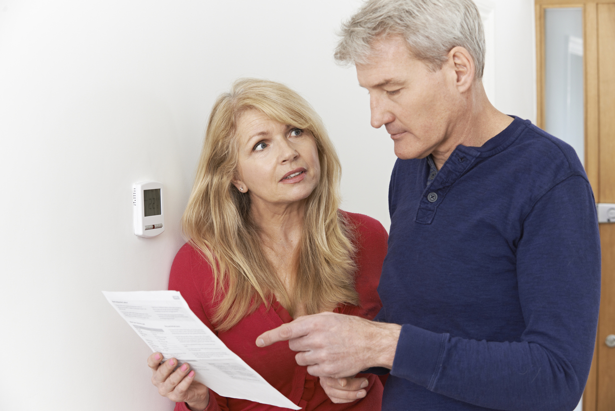 Couple looking at energy bill next to thermostat